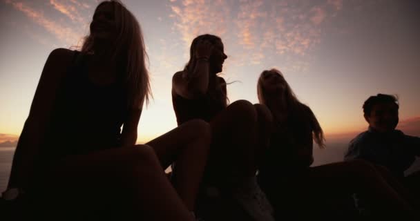 Adolescentes sentados en rocas juntos al atardecer — Vídeo de stock