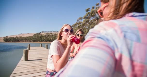 Девочки-подростки смеются на причале во время летних каникул — стоковое видео