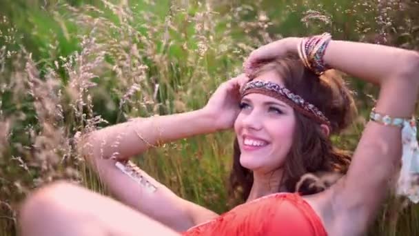 Boho meisje glimlachend liggen in een veld — Stockvideo