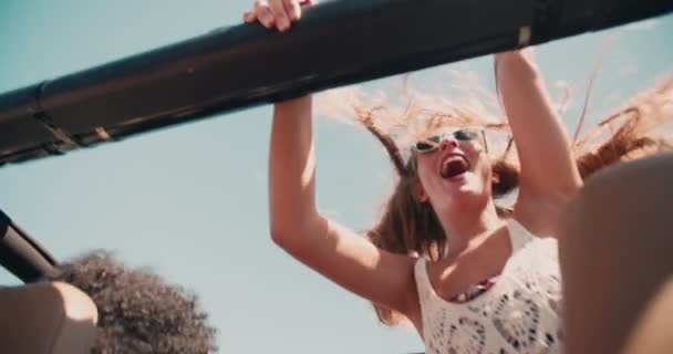 Blond tonårstjej står och vinkar glatt — Stockvideo