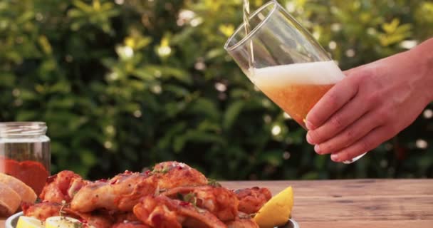 Man gieten glas bier met kippenvleugels — Stockvideo