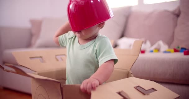 Baby boy in a box with a plastic bowl — Stock Video