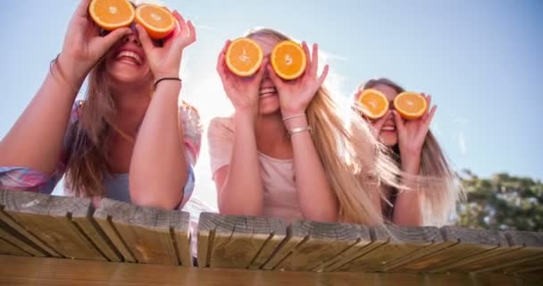 Teen girl friends holding up oranges for eyes — Stock Footage Teen girl friends holding up oranges for eyes Royalty Free Stock Footage