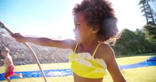 Chica africana rociando agua de manguera de jardín — Vídeo de stock