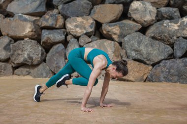 Spor kıyafetleri giymiş, spor yaparken taş duvarın yanında dirsek dirseğe tahta döşeme yapan pozitif zayıf kadının yan görüntüsü.