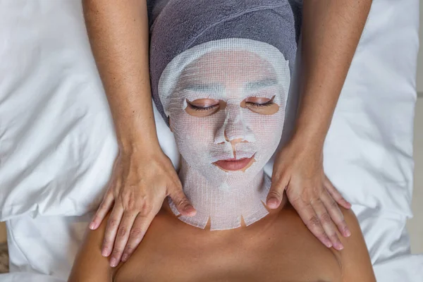 在温泉沙龙接受美容师的双肩按摩 俯瞰一位满脸纱布进行皮肤治疗的妇女 温泉的概念 — 图库照片