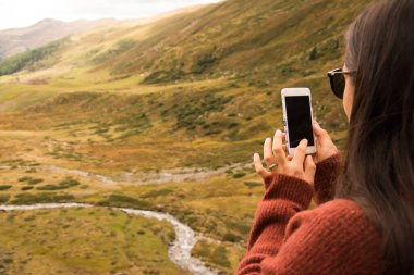 Kadın, İsviçre 'deki bir manzaranın akıllı telefonuyla fotoğraf çekiyor.