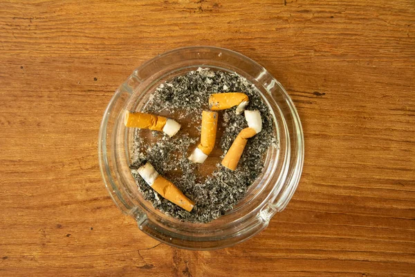 Full ashtray with cigarette butt on wooden background