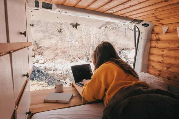 Vanlife - Junge Frau arbeitet im Campingbus inmitten der Natur am Notizbuch lizenzfreie Stockbilder