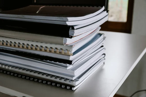 Stack av rapporter ligger på ett skrivbord redo för granskning Stockfoto