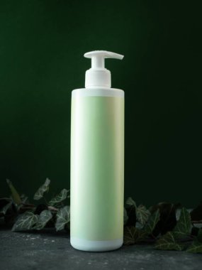 Kozmetik krem için boş pompa şişesi ya da sarmaşık yapraklı koyu yeşil arka planda sabun