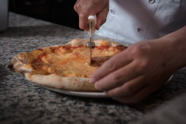 Pizzayı dilimlere ayıran şefin elleriyle yapılan zanaatkar pizzası.