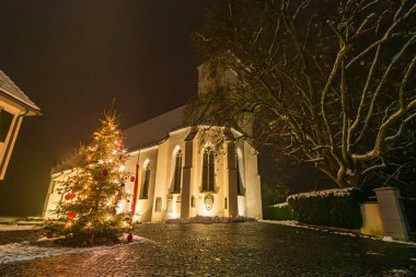 Upper Swabia 'daki Ostrach yakınlarındaki Koenigseggwald' da renkli ışıklandırmayla güzel bir Noel ortamı.