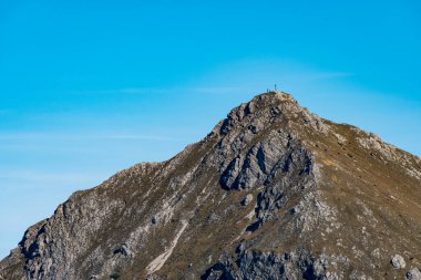 Yürüyüşçüler Allgaeu Alpleri 'ndeki kayalık araziler ve yemyeşil yemyeşil alanların ortasındaki zirveye doğru yükselirken berrak bir sonbahar gününün dingin güzelliğini yakalıyorum.