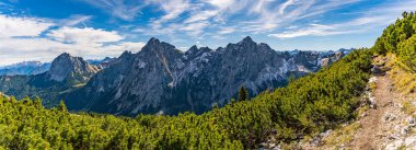Nefes kesen bir panoramik manzara, sonbaharın dingin güzelliğini, berrak havayı ve engebeli bir dağ yolu boyunca altın renklerini yakalar, sükunet ve macerayı anımsatır.