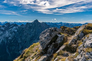 Engebeli dağ tepelerinin ve kayalık arazinin nefes kesici panoramik manzarası Tannheimer Vadisi 'ndeki kıtır sonbahar yürüyüşü sırasında sükunet ve macerayı çağrıştırıyor.