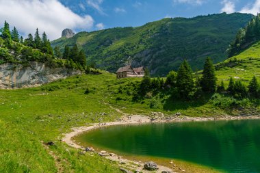 Sakin bir göl manzarası, Alpstein Dağları 'ndaki açık gökyüzünün altında canlı yeşillikler ve yüksek zirvelerle el değmemiş İsviçre Alplerinde barış ve macerayı çağrıştırıyor.