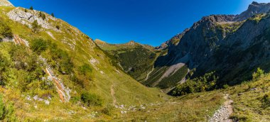 Nefes kesici bir panoramik manzara, Gadental vadilerinin engebeli güzelliğini, dağlık patikalarını, berrak gökyüzünün altındaki dinginliği ve macerayı yakalar.