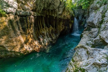 Nefes kesici zümrüt şelalesi engebeli kanyon duvarlarından zarif bir şekilde akıyor, Slovenya 'nın el değmemiş Soca Vadisi' nde sükunet ve doğal mucizeyi çağrıştırıyor.