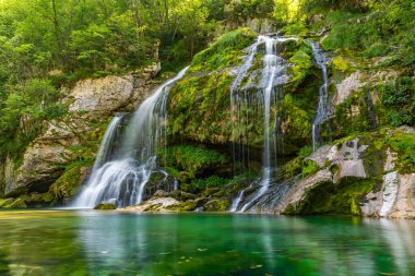 Görkemli şelale zarif bir şekilde zümrüt yeşilliğinin ortasında akıyor, Slovenya 'nın el değmemiş Soca Vadisi' nde sükunet ve doğal mucizeyi çağrıştırıyor.