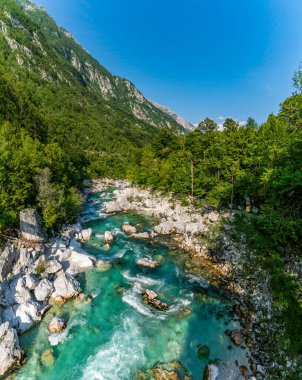Slovenya 'nın Soca Vadisi' ndeki pürüzsüz kayaların üzerinde kristal berraklığında akan sular, parlak güneş ışığı altında sükunet ve doğal güzelliği çağrıştırıyor.