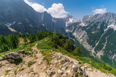 Slovenya 'nın el değmemiş Triglav Milli Parkı' ndaki dinginlik ve macerayı çağrıştıran yemyeşil ve engebeli tepelerde nefes kesici bir dağ yolu esiyor.