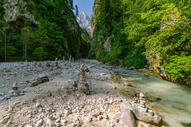 Sakin bir dağ akıntısı, yüksek uçurumlar ve istiflenmiş taşlarla çerçevelenmiş, Slovenya yakınlarında Martuljek Şelaleleri 'ni şaşkına çeviren barış ve keşifleri çağrıştıran yemyeşil bir çayırda esiyor.