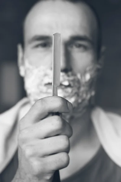 Young man holding straight razor. Black and white — Stock Photo, Image