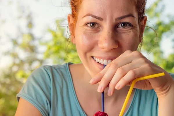 Junge Frau lächelt und genießt frischen Smoothie an einem sonnigen Tag — Stockfoto