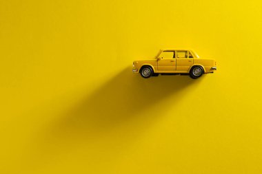 Sarı arka planda, uzun ve yan gölgeli sarı bir oyuncak arabanın sol tarafı..