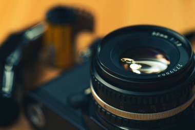 Tahta arka planda 35 mm 'lik negatif bir film olan analog bir kameranın canlı görüntüsü.