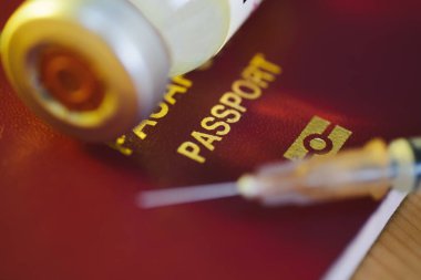 Koronavirüs aşısı şişesi ve aşı pasaportu olarak kırmızı renkli hindilerin olduğu bir şırıngayı yakın plan çek..