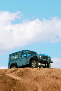İzmir, Türkiye - 20 Nisan 2021: Kum ve mavi zemin üzerinde mavi renkli 4x4 SUV Car 'ın yakın çekimi.