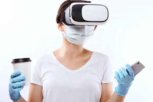 Person of 2021 with a virtual reality glass, a take away coffee cup, a medical face mask for coronavirus disease, medical gloves and a smart phone for social media.