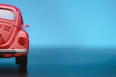 Mavi arka planda kırmızı renkli oyuncak bir arabanın kısmi dikiz görüntüsü..