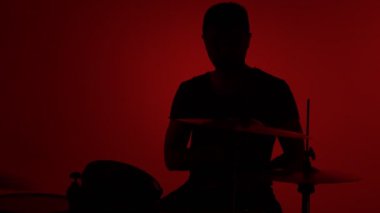 Siluet davulcusu kırmızı arka planda davul çalıyor. Stüdyo görüntüleri.