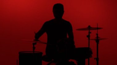 Siluet davulcusu kırmızı arka planda davul çalıyor. Stüdyo görüntüleri.