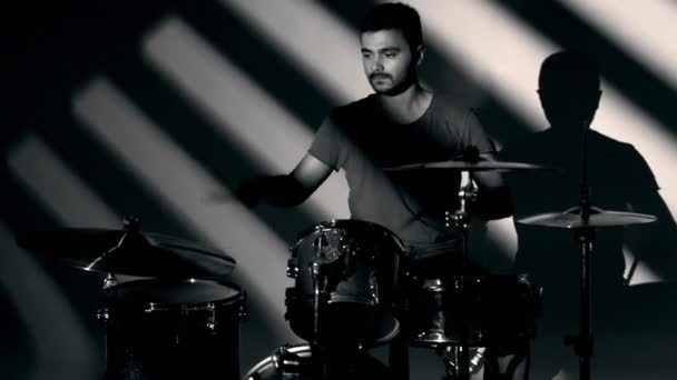 연주자가 무늬의 그림자와 드럼을 연주하는 흑백으로 촬영되었다 — 비디오