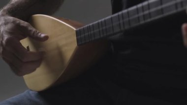 Kopuz çalarken, Baglama adında üç telli bir telli çalgıdır..