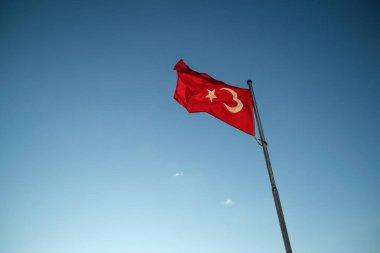 Mavi arka planda dalgalanan bir Türk bayrağı.