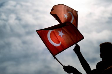 İzmir, Türkiye - 9 Eylül 2021: Mavi ve bulutlu bir gökyüzünde ve özgürlük gününde Türk bayraklarını tutan İki El İzmir.