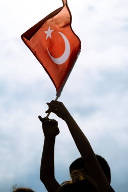 Sıcak bulutlu bir gökyüzünde dalgalanan Türk bayrağını yakından çek.