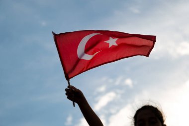 Sıcak bulutlu bir gökyüzünde dalgalanan Türk bayrağını yakından çek.