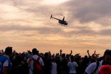 İzmir, Türkiye - 9 Eylül 2021: İzmir 'in özgürlük gününde ellerinde Türk bayrakları ve Atak helikopteriyle gösteri yapan insanlar.