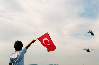 İzmir, Türkiye - 9 Eylül 2021: Türk bayrağı ve polis helikopterleri taşıyan bir çocuk İzmir 'in özgürlük gününde gökyüzünde gösteri yapıyor.