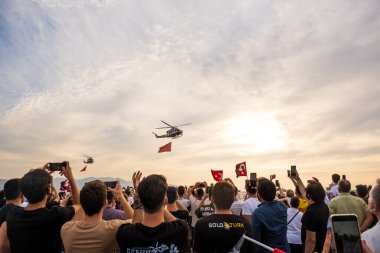 İzmir, Türkiye - 9 Eylül 2021: Bir gösteri için İzmir 'in özgürlük gününde, dev bir Türk bayrağıyla gökyüzünde uçan Türk Sahil Güvenlik helikopteri. Çerçevede Türk bayraklarıyla kalabalık var.