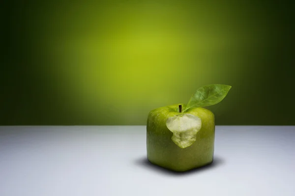 Bitten, green cube apple. — Stock Photo, Image