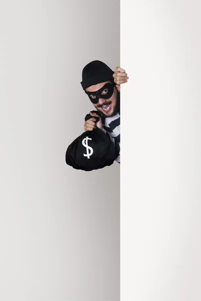 Lächelnder Einbrecher hinter einer Mauer mit einem Geldbeutel — Stockbild Einbrecher — Stockfoto