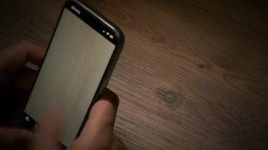 Bir telefon ekranının yakın plan görüntüsü olan zaman ayarlı bir video. Sosyal medyada hızla ilerleyen dijital alışkanlığı yakalayan bir başparmağı sürekli aşağı ve yukarı kaydırıyor.