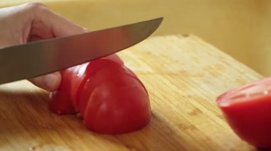 Taze domates doğrayan bir kadın salata hazırlamak için tahta kesme tahtasının üzerinde bıçak kullanıyor.